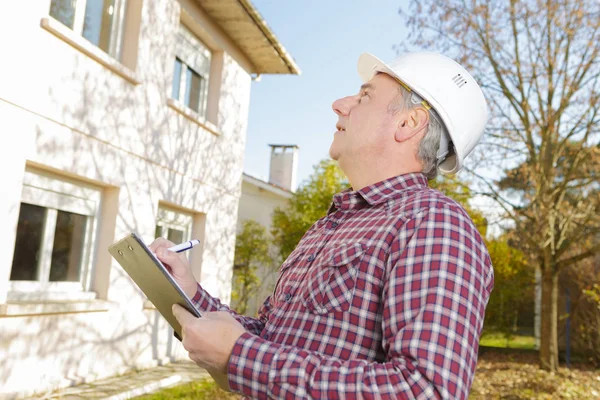 Architect writing on clipboard while looking away outside building — Stock Photo, Image