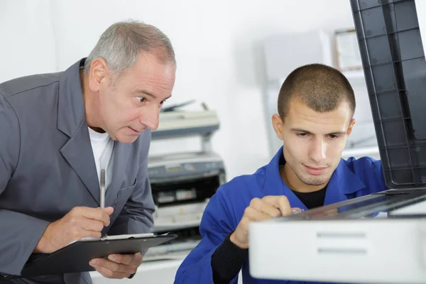 Aprendiz aprendendo a consertar uma impressora — Fotografia de Stock