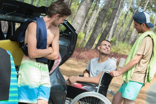 Tre amici che arrivano in spiaggia uno è handicappato — Foto Stock