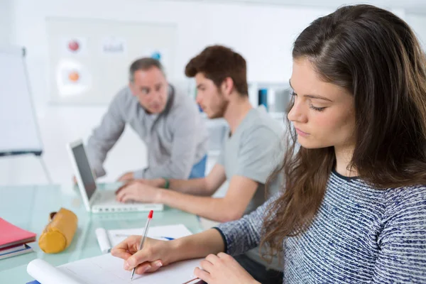 Serieuze jonge vrouwelijke student, het maken van notities in de klas — Stockfoto