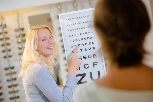 Mulher lendo de um gráfico de teste de olho — Fotografia de Stock