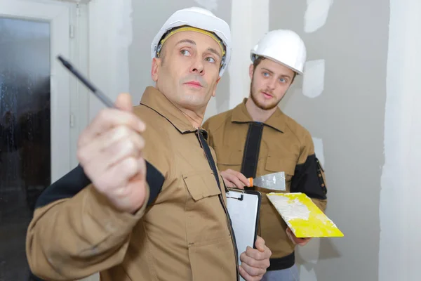 Jovem estucador masculino na renovação da parede interior seguindo conselho do gerente — Fotografia de Stock