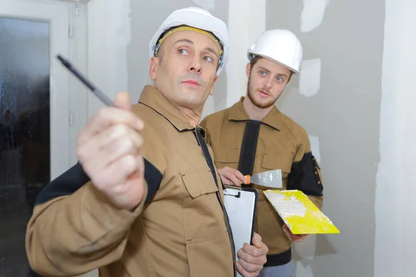 Joven yesero masculino en la renovación de la pared interior siguiendo el consejo del gerente —  Fotos de Stock