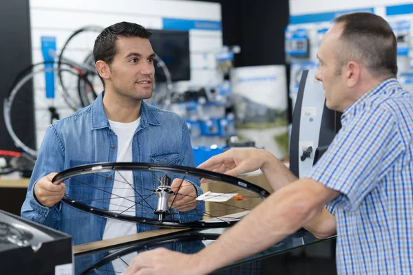 Hombre positivo en busca de nueva bicicleta de carreras en la tienda de deportes —  Fotos de Stock