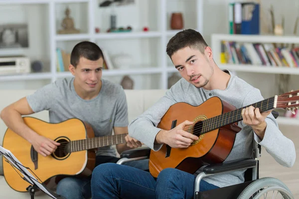 Homens jovens tocando guitarra no sofá interior — Fotografia de Stock