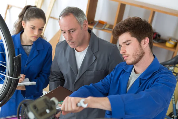 Bicycle mechanic and apprentice repairing a bike in workshop — Stock Photo, Image