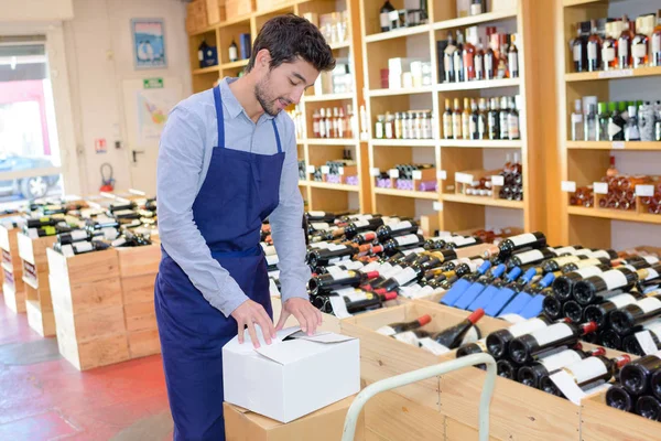 Prodávající muž nosí zástěru ve vinotéce — Stock fotografie