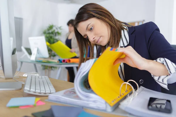Kvinnliga kontorist snärta genom pappersarbete i mappen — Stockfoto