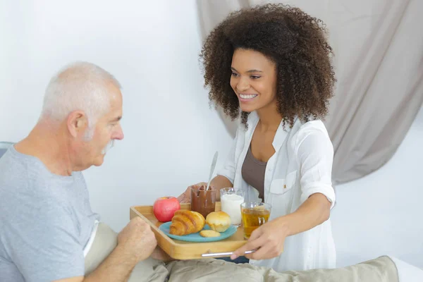 Joven mujer dando desayuno a viejo hombre —  Fotos de Stock