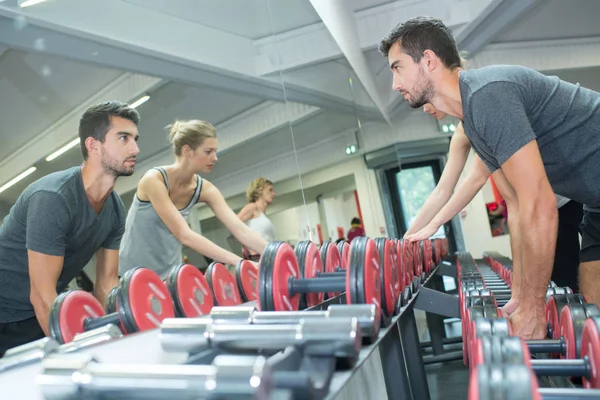 Personer i gym att välja vikter, återspeglas i spegeln — Stockfoto