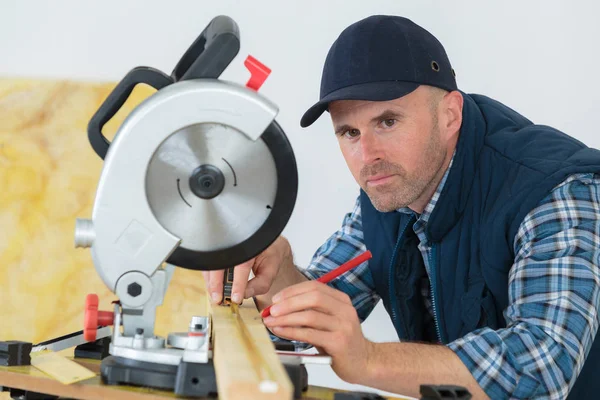 Retrato del hombre midiendo madera bajo sierra circular — Foto de Stock