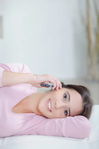 Mujer joven en casa acostada y llamando por teléfono — Foto de Stock