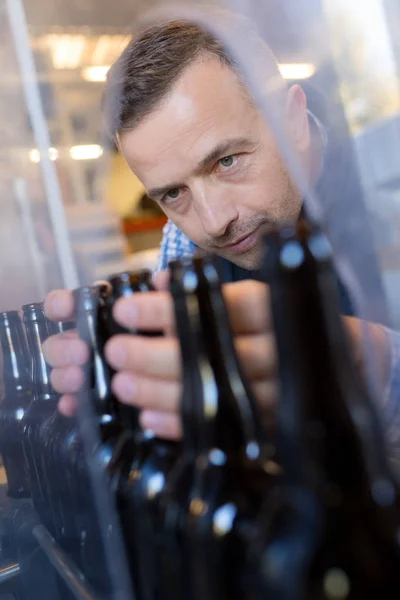 Trabajador masculino en delantal que opera equipos de embotellado en cervecería —  Fotos de Stock