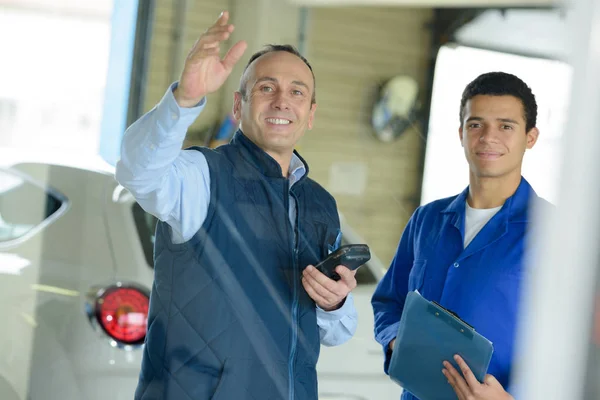 Coleagues waving at the camera in the factory — Stock Photo, Image