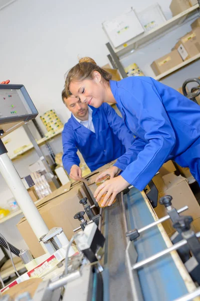 Werknemers verpakking van percelen met plakband in magazijn — Stockfoto