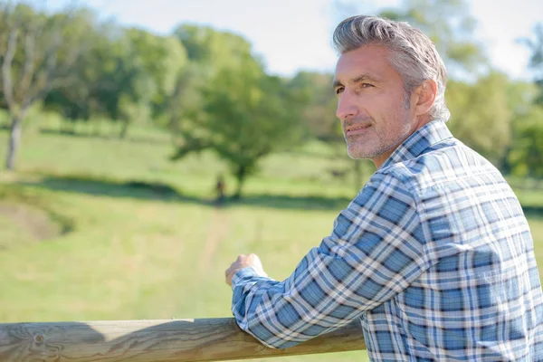 Man leaning on wooden fence — Stock Photo, Image