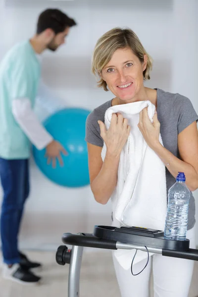 Woman after exercising with her experienced young physiotherapist — Stock Photo, Image