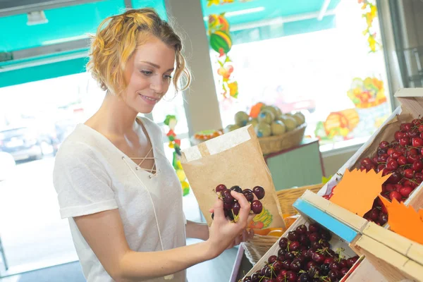 Giovane donna che acquista ciliegie in un mercato — Foto Stock