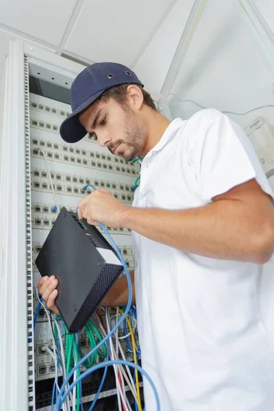 Elektrikçi internet sunucusunu güç panosuna bağlıyor — Stok fotoğraf