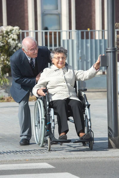 Starší muž tlačí žena na invalidním vozíku — Stock fotografie