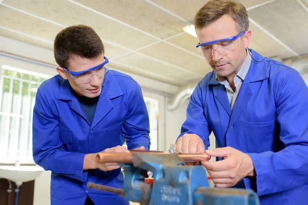 Dva inženýři pracující na měděné trubice konají ve svěráku — Stock fotografie