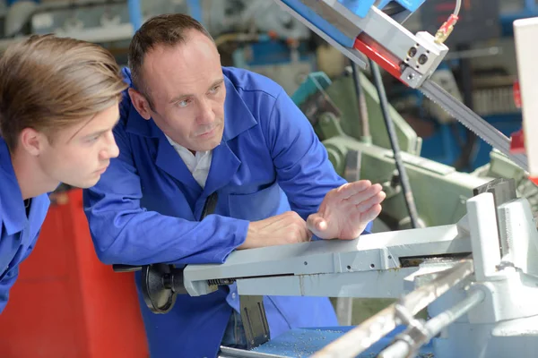 Uomo che spiega il lavoro della macchina al tirocinante — Foto Stock