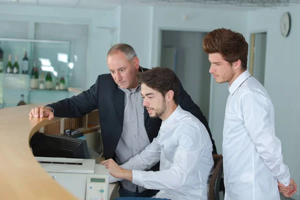 Two happy males receptionist and manager standing at hotel counter — Stock Photo, Image