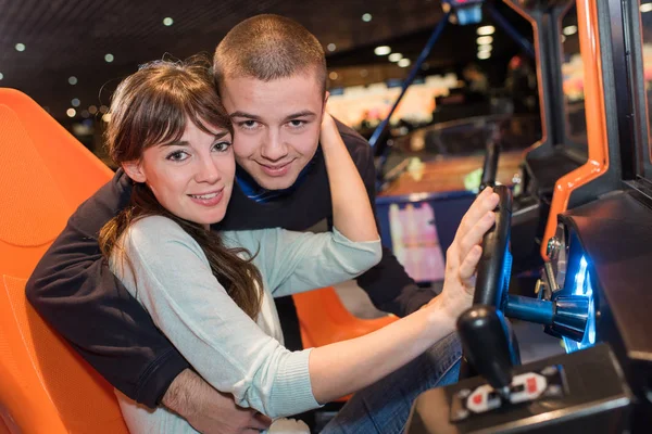 Молода пара сміється в симуляторі гоночного автомобіля — стокове фото