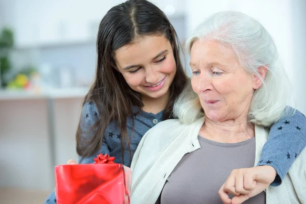 Kleindochter Een Cadeautje Geven Aan Haar Verrast Grootmoeder — Stockfoto
