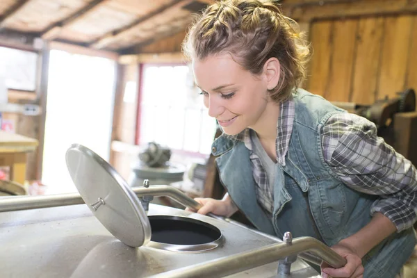 Kobiece pracownik otwarcie kranu na zbiorniku w przemysłowych warsztaty — Zdjęcie stockowe