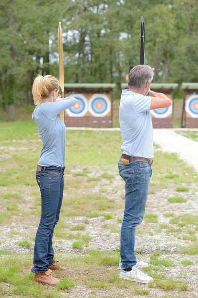 Pareja practicando tiro con arco y tiro con arco — Foto de Stock