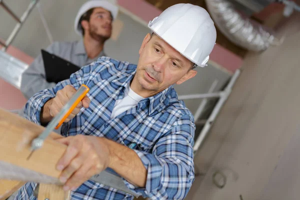 Homme à tout faire coupant du bois avec scie à main en atelier — Photo