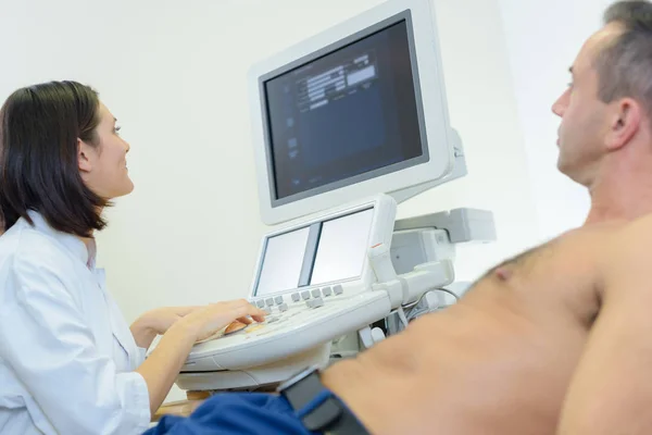 Joven doctora usando ultrasonido en paciente masculino — Foto de Stock