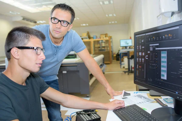 Двое мужчин в очках работают за компьютером — стоковое фото