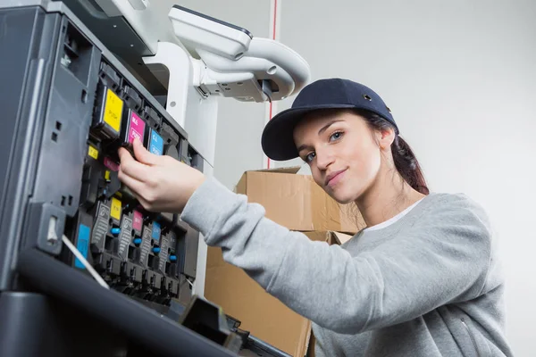 Técnico feminino trocando cartuchos de tinta de uma fotocopiadora — Fotografia de Stock