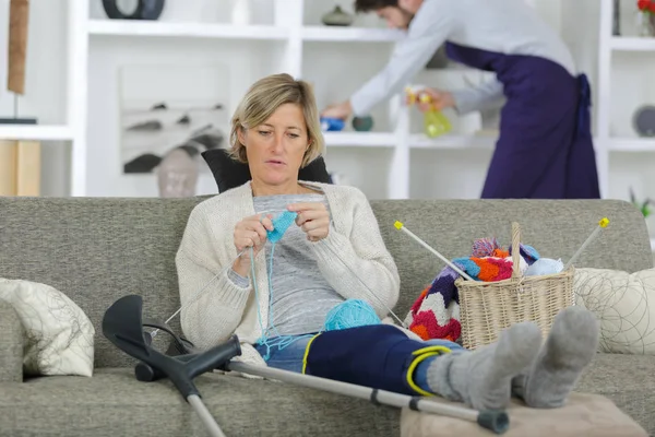 Donna con gamba intonacata seduta sul divano a casa — Foto Stock