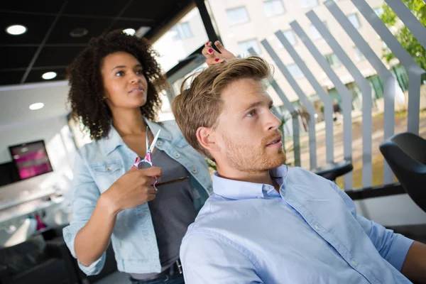 Mulher faz o corte de cabelo para o homem no salão de cabeleireiro — Fotografia de Stock