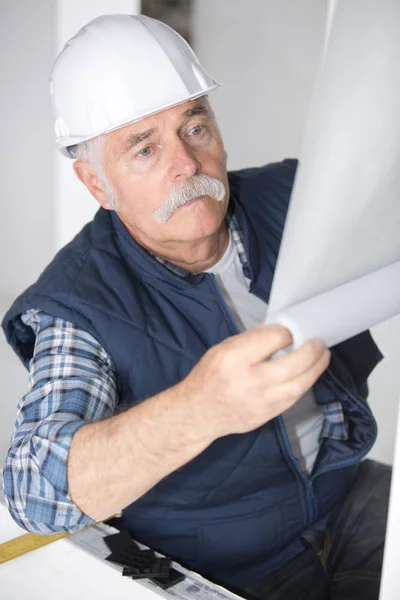 Handyman sênior colocando papel de parede nas paredes brancas — Fotografia de Stock