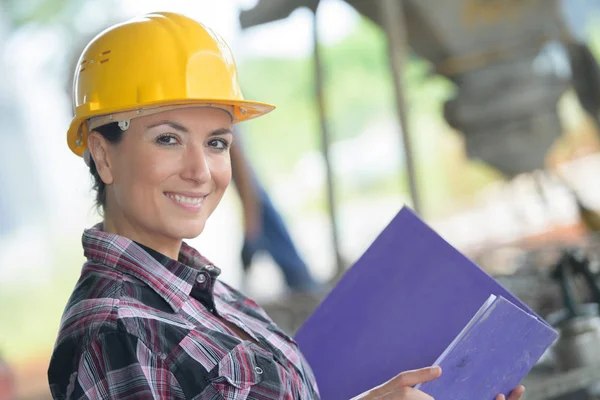 Portrait of woman wearing hardhat and holding a folder — Stock Photo, Image