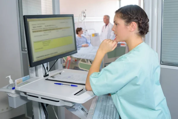 Enfermeira ler anotações do paciente na tela do computador — Fotografia de Stock