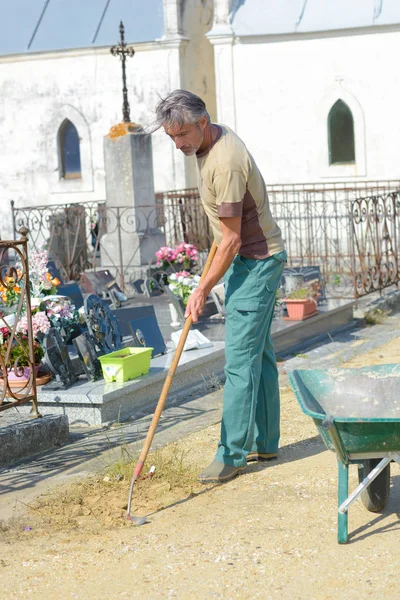 Hombre rastrillando piedras en el cementerio —  Fotos de Stock