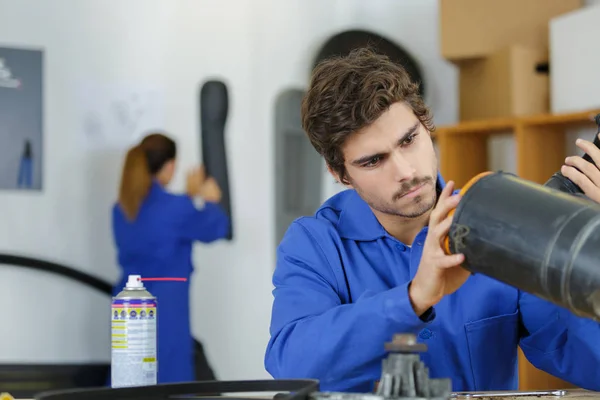 Jeune mécanicien huilant un piston de moto — Photo