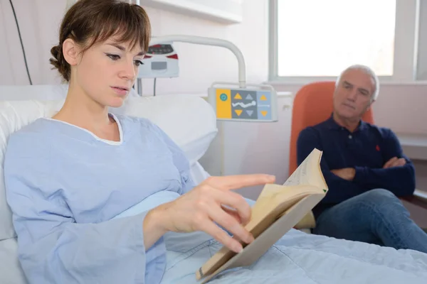 Женщина в больничной койке читает книгу — стоковое фото