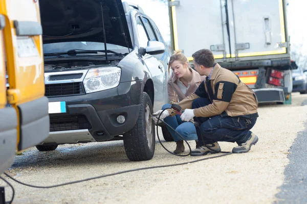 Mechanic fixing a car problem on the road — стоковое фото