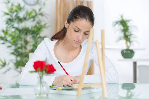 Ung kvinna skriver vid bordet — Stockfoto
