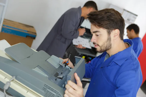 Joven reparador fijación fotocopiadora — Foto de Stock
