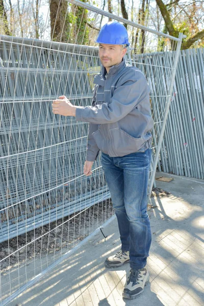 Uomo che trasporta recinzione in metallo — Foto Stock