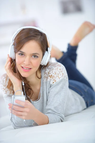 Jonge vrouwen die luisteren naar de muziek van smartphone op bed — Stockfoto