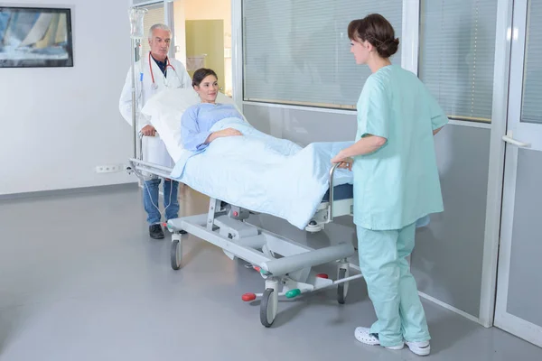 Enfermeras moviendo al paciente por el pasillo del hospital —  Fotos de Stock