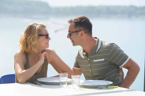 Fiatal pár eszik étterem teraszán, kilátással a tóra — Stock Fotó